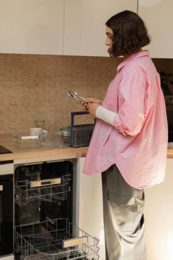 Mutfakta elinde temiz çatal bıçak tutan genç bir kadın.