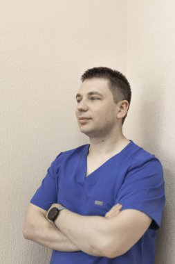 Erkek bir doktor duvara yaslanıyor.