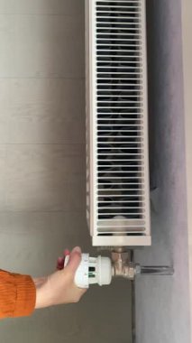 Bir kadının eli radyatörün sıcaklığını ayarlar.