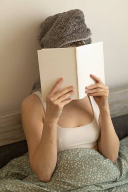 Bir kadın evde kitap okuyor.