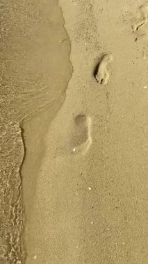 Deniz kenarındaki kumlu sahilde ayak izleri var.