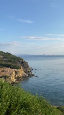 Denizin su yüzeyi, tepenin manzarası, kayaların manzarası, ufuk çizgisi.