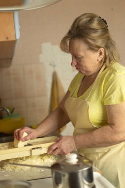 Ev mutfağında taze lahana doğrayan olgun bir kadın.