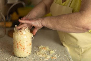Ev mutfağında taze lahana doğrayan olgun bir kadın.