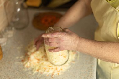 Ev mutfağında taze lahana doğrayan olgun bir kadın.
