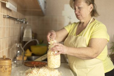Ev fermantasyon süreci: doğranmış lahana ve havucu kavanozlara sıkıca paketlemek.