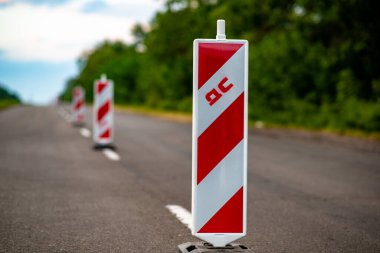 Yol inşaatı sırasında trafik ayrılması için tasarlanmış parlak renkli dikey yol kalınlıkları. Güvenliğin arttırılması ve araç akışının yönlendirilmesi için ideal olan bu kalıcı engeller, etkin yol çalışması yönetimi için gereklidir. Resmetmek için mükemmel 