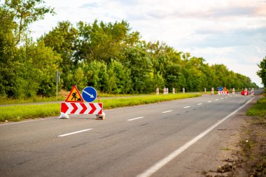 Yol tabelaları ileride inşaat çalışması olduğunu gösteriyor, sürücüleri sapma ve güvenlik önlemlerine karşı uyarıyor. Trafik yönetimi, kentsel gelişim veya altyapı projelerini resmetmek için ideal. Herhangi bir taşımacılık veya inşaatla ilgili içerik için hayati bir görüntü.