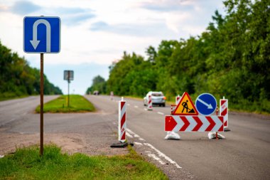 Yol tabelaları ileride inşaat çalışması olduğunu gösteriyor, sürücüleri sapma ve güvenlik önlemlerine karşı uyarıyor. Trafik yönetimi, kentsel gelişim veya altyapı projelerini resmetmek için ideal. Herhangi bir taşımacılık veya inşaatla ilgili içerik için hayati bir görüntü.