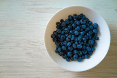 Beyaz kasedeki taze yaban mersinleri canlı renklerini ve göz sağlığı için sağlık faydalarını vurguluyor. Antioksidan ve vitaminlerle dolu bu lezzetli böğürtlenler iyi görüşü ve genel sağlığı teşvik ediyor ve onları iyileşmeye mükemmel bir katkı yapıyor.