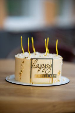 Mumlarla süslenmiş nefis ve şık bir doğum günü pastası. Zarif altın harflerle. Kutlamalar için mükemmel..
