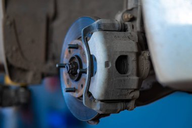 Karmaşık tasarım ve mühendisliği vurgulayan fren diskiyle bir araba merkezinin yakın çekimi. Otomotiv tamiri, bakım ve teknoloji temaları için ideal.