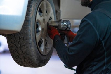 Yetenekli bir tamirci, otomotiv tamiri konusunda uzmanlık ve hassasiyet gösteren bir araba tekerleğini etkili bir şekilde çıkarmak için pnömatik silah kullanır. Bu aksiyon dolu resim profesyonel araba bakımının özünü yakalar ve meyvenin önemini gösterir