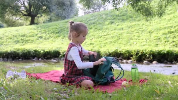 Ein Schulmädchen Sammelt Bücher Einem Rucksack Während Sie Der Natur — Stockvideo