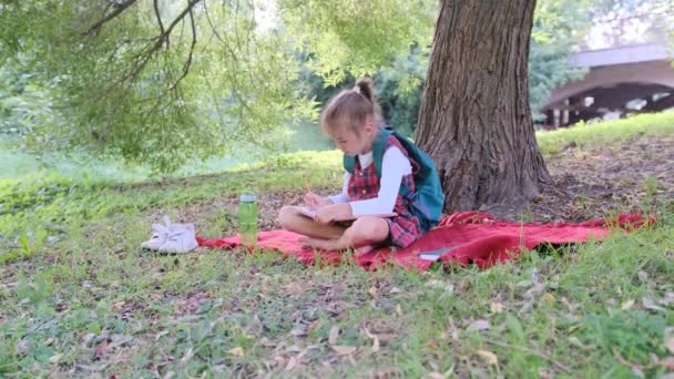 Przemyślana Dziewczynka Rysuje Szkicowniku Siedząc Lesie Pod Drzewem Słoneczna Pogoda — Wideo stockowe