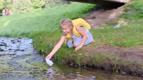 Девушка Запускает Бумажную Лодку Быстрой Реке — стоковое видео