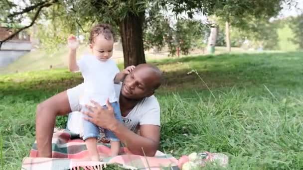 Afroamerikansk Man Leker Med Ett Litet Barn Som Ligger Gräset — Stockvideo