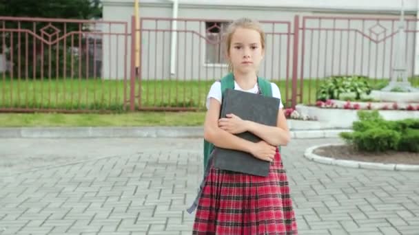 那女孩上学去了 那孩子手里拿着一本大课本 这个女孩带着背包和一本书去上学 — 图库视频影像