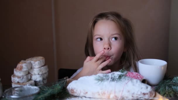 女の子はテーブルに座っている間に盗まれたクリスマスから指で粉砂糖を試してみてください — ストック動画