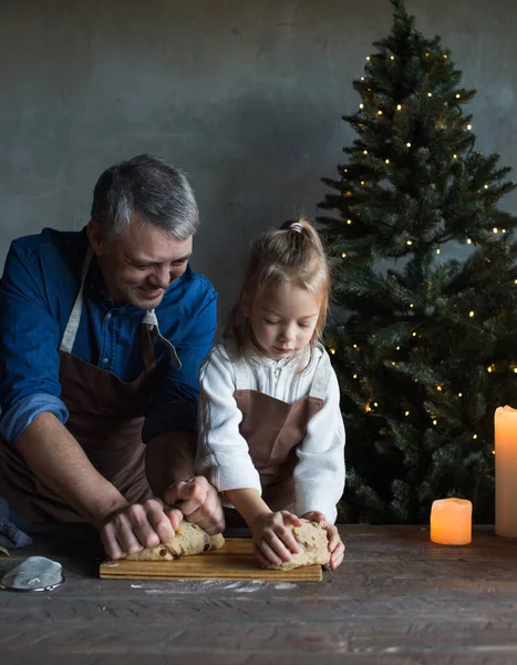 dad and daughter knead dough together on the table and prepare Christmas treats. Family traditions