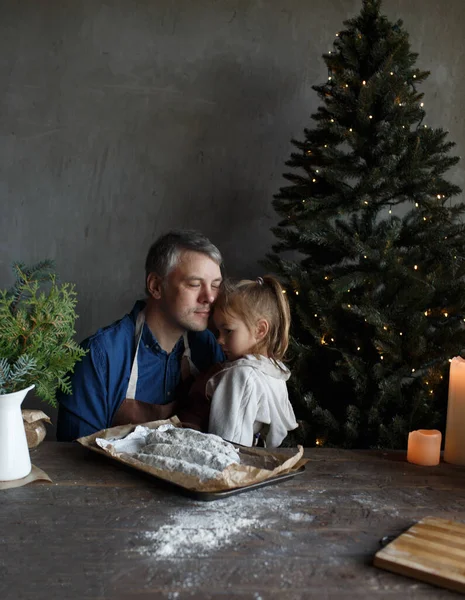 loving dad hugs little daughter while making Christmas pastries