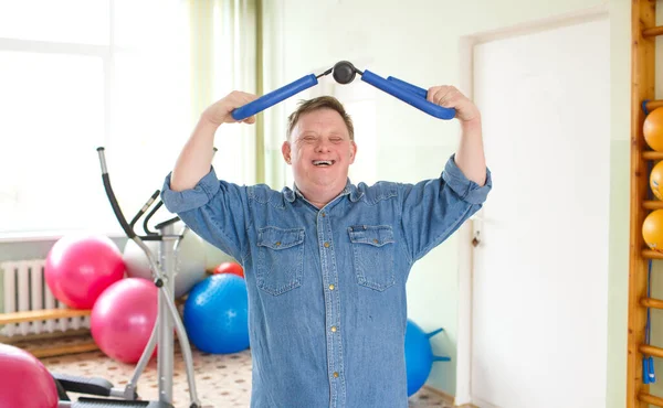 a man with down syndrome works out with a gym in the gym