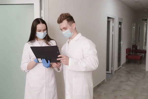 doctors discuss the medical report in the hospital. A young female doctor and a male doctor check the patient\'s clinical report online. Medical staff standing in the corridor of a private clinic.