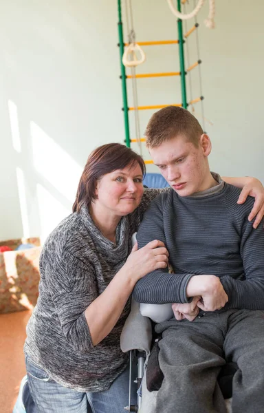 a boy with disabilities in a rehabilitation center with special needs next to his mother.