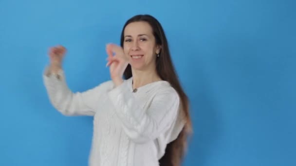 一个黑发女孩 穿着白衬衫 在蓝色的背景上时髦地跳舞 — 图库视频影像