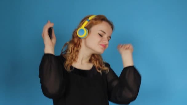 Młoda Dziewczyna Żółtych Słuchawkach Tańcząca Niebieskim Tle — Wideo stockowe