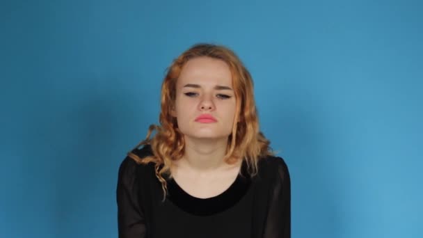 Μια Νεαρή Σοκαρισμένη Γυναίκα Στέκεται Απομονωμένη Ένα Μπλε Φόντο Κοιτάζοντας — Αρχείο Βίντεο
