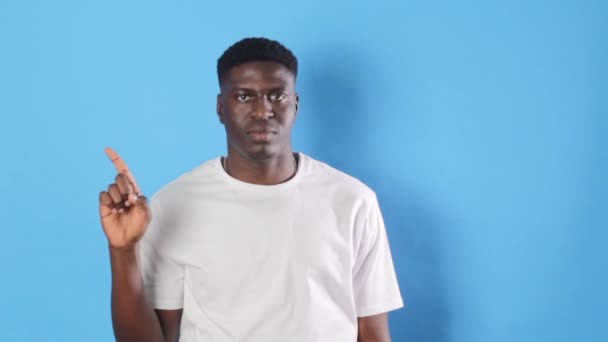 Ένας Νεαρός Όμορφος Αφρικανός Ένα Απομονωμένο Μπλε Φόντο Δείχνει Δάχτυλό — Αρχείο Βίντεο