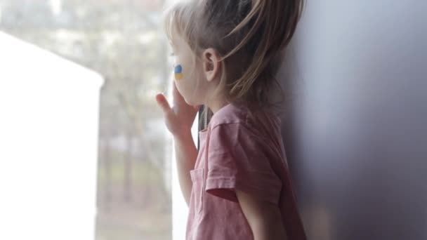 Маленькая Девочка Украинским Флагом Нарисованным Лице Грустно Смотрит Окно — стоковое видео