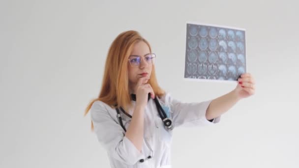 Uma Jovem Médica Ruiva Estuda Imagens Tomografia Fundo Branco — Vídeo de Stock