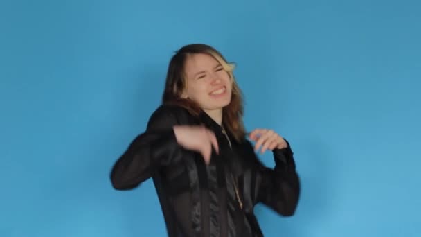 Счастливая Беззаботная Женщина Черной Блузке Танцует Смотрит Камеру Синем Фоне — стоковое видео