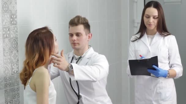 一位年轻的男医生正在诊所检查一位病人 — 图库视频影像