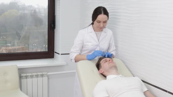 診療所の女性美容師は 毛細血管の血流を増加させ 皮膚を若返らせるために男性の顧客の皮膚に二酸化炭素を注入します カルボン酸療法 — ストック動画