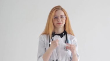 A female doctor in uniform holding a syringe against an isolated background, a young nurse, hospital staff.