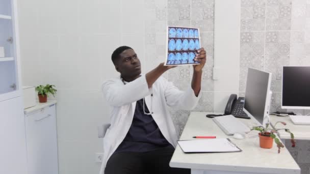 African American Doctor Attentively Examines Mri Images While Sitting Office — Stockvideo