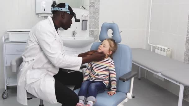 Афро Американский Отоларинголог Внимательно Осматривает Маленькую Девочку Время Приёма Медицинском — стоковое видео