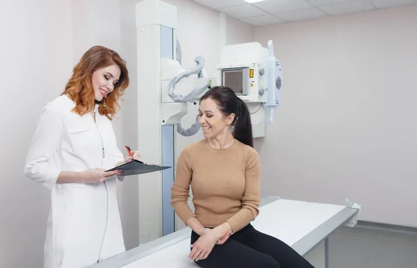 a female radiologist communicates with a patient in the X-ray room before the procedure begins
