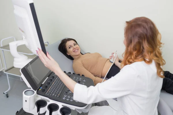 a female doctor performs ultrasound diagnostics of the intestine, abdominal cavity, right lobe, liver, bile ducts, gallbladder. Soft tissue examination using a portable sensor device with a convex probe.