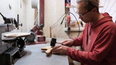 An adult male carpenter working with tools in his carpentry workshop making wooden toys