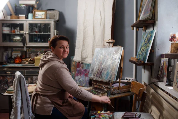 a female artist is engaged in painting in a creative studio.
