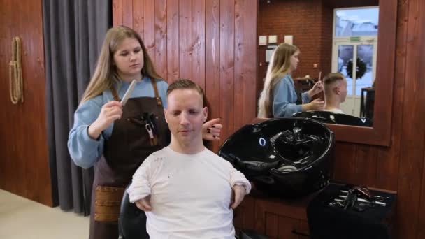 美容師の女の子は障害のある若い男のために髪をします — ストック動画