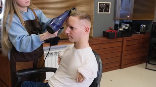 Ein Friseurmädchen Frisiert Einen Mann Mit Behinderungen Trocknet Ihm Den — Stockvideo
