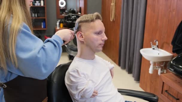 手の先天性病理を持つ若い男が理容室で髪をしてる — ストック動画