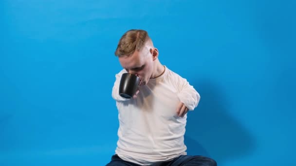 Mężczyzna Niepełnosprawny Pije Herbatę Kubka Niebieskim Odosobnionym Tle — Wideo stockowe