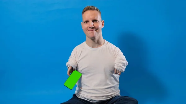 Man Disabilities Sitting Isolated Blue Background Holding Smartphone His Hand — Stock Photo, Image