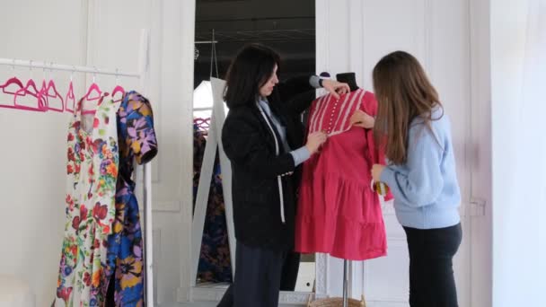 两个女设计师在缝纫车间里检查一件挂在模特身上的衣服 — 图库视频影像